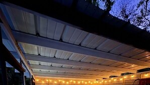 Una terrazza esterna con area salotto coperta, una piscina e uno scivolo.