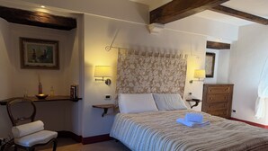 A bedroom with a bed, bedside lamps, a chair, a dresser, and a painting on the wall.