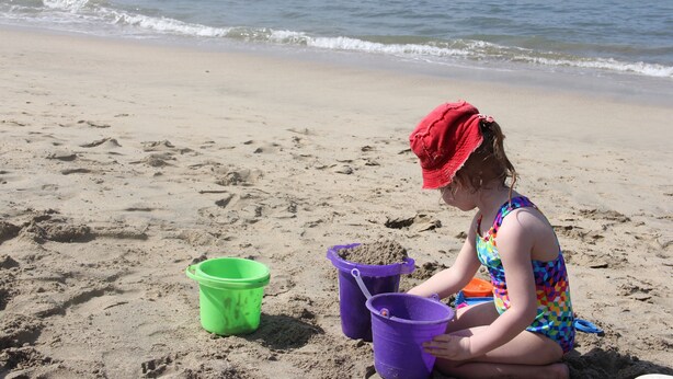 Une scène de plage où un enfant joue avec du sable et des seaux.