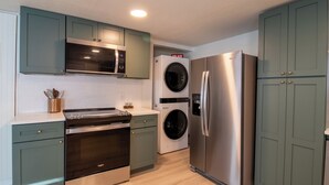 Een moderne keuken met een roestvrijstalen koelkast, een dubbele oven, een magnetron en een wasmachine.