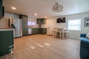 A modern kitchen with a dining area, wooden flooring, and a ceiling light fixture. - The Cozy Cabana 2BR New Port Richey Sims Park (New Port Richey)