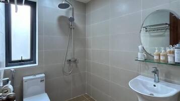 Ein Badezimmer mit Toilette, Bidet, Dusche und Waschbecken mit Spiegel darüber.