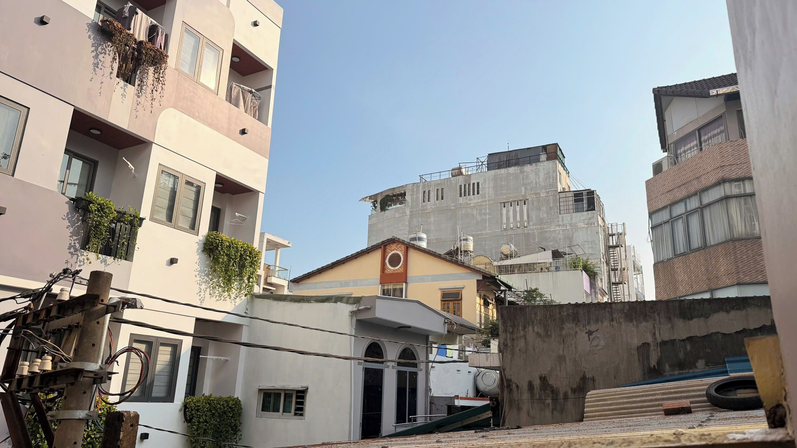 A multi-story residential building with balconies, a visible water tank, and a staircase leading to an upper level.