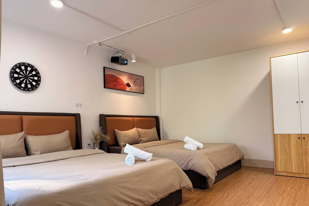 Habitación de hotel con dos camas, un dardo, un proyector y un armario.