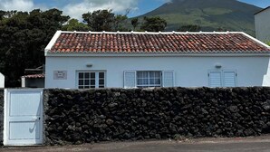 A white building with a tiled roof, a stone wall, and a gate. - Retiro dos Cabritos (Madalena)