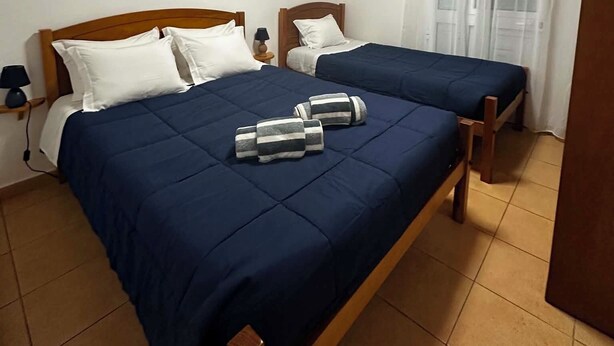 A room with two wooden beds, a ceiling light, and a window with curtains. - Retiro dos Cabritos (Madalena)