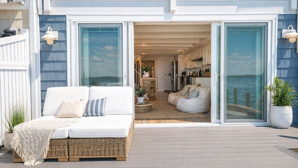 Et moderne hus med balkon, hvid sofa og spiseområde.