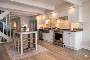 Eine moderne Küche mit weißen Schränken, einem eingebauten Backofen und einem Essbereich mit Tisch und Stühlen.