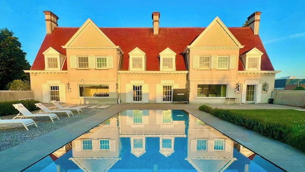Een groot huis met een zwembad ervoor.
