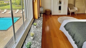 Een slaapkamer met een groot raam, een bed, een stoel en een kledingkast.