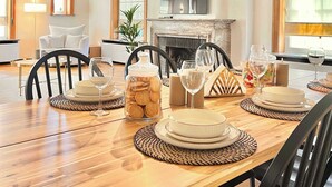 Een eetgedeelte met een houten tafel gedekt voor vier personen, een open haard en een televisie op de achtergrond.