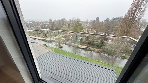 Une vue depuis une fenêtre, donnant sur une rivière, un pont et des bâtiments au loin.