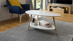 Un salon moderne avec une table ronde, un fauteuil bleu, un téléviseur à écran plat et une grande horloge murale.