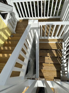 Eine Holzterrasse mit weißen Geländern, einer kleinen Öffnung und einem Holzboden.