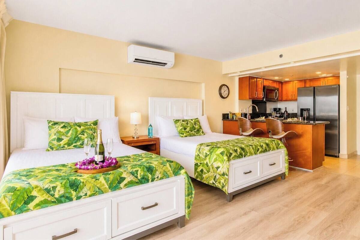 Ein Hotelzimmer mit zwei Betten, einer Küchenzeile und einer Uhr an der Wand.