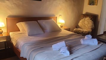 Ein Schlafzimmer mit einem Bett, zwei Nachttischlampen, einem Nachttisch, einem Sessel und Wandbildern.