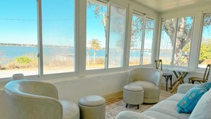 Une pièce avec vue sur un plan d’eau, un canapé, deux fauteuils, une petite table et une chaise.