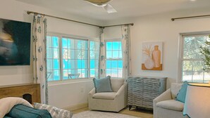 Un salon avec un ventilateur de plafond, deux canapés, une table d’appoint et un tableau accroché au mur.