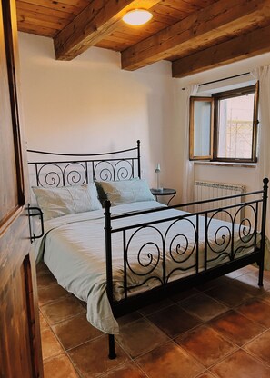 Ein Schlafzimmer mit einem Metallbettgestell, einem Nachttisch, einer Lampe und einem Fenster mit Blick.