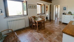 A kitchen with a dining table, chairs, a radiator, and a window. - Casale Milleluci - double apartment in the countryside 10 min from the sea (SENIGALLIA)