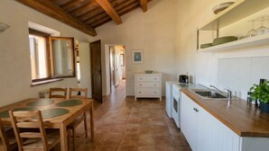 A kitchen with a wooden ceiling, a dining area with a table and chairs, and a view of a hallway. - Casale Milleluci - double apartment in the countryside 10 min from the sea (SENIGALLIA)