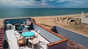 Um alpendre à beira-mar com mobiliário de exterior e vista para o oceano.