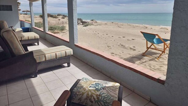 Uma área de estar coberta ao ar livre com vista para a praia e o oceano.