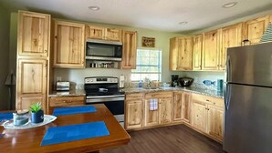 A kitchen with wooden cabinets, a stainless steel refrigerator, a microwave, and a stove.