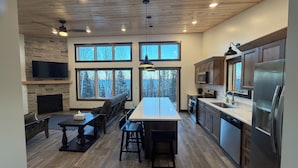 A modern kitchen with a central island, built-in appliances, and large windows offering views of the outdoors.