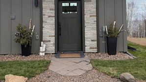 A modern building with a stone facade, a dark door, and two potted plants.