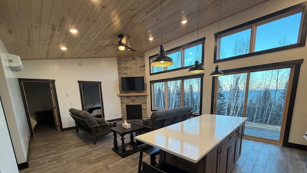 A spacious kitchen with a large island, wooden flooring, and a stone fireplace.