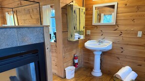 L’intérieur d’une cabane en bois, avec une cheminée, un évier, un miroir et un extincteur.