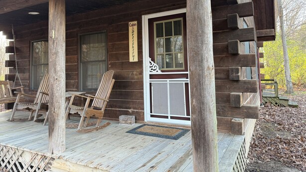 Une cabane dotée d’une véranda, de fauteuils à bascule et d’une porte sur laquelle est inscrit : « Cabane ravissante ».