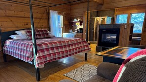 L’intérieur d’un chalet confortable, avec un lit, un canapé, une cheminée et un téléviseur.