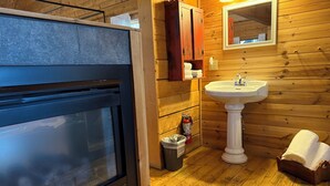 A wooden interior with a built-in oven, a pedestal sink, and a mirror above it.