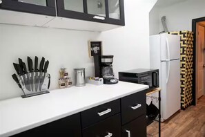 A kitchen with a coffee machine, microwave, refrigerator, and black cabinets. - Montrose / King Bed / Close to Downtown and Med Ctr (Houston)