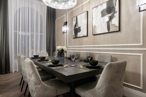 Comedor con una mesa rectangular dispuesta para cuatro, sillas tapizadas, un florero con flores y arte abstracto en la pared.