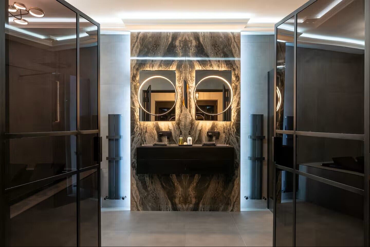 Ein modernes Badezimmer mit Waschtisch aus Marmor, zwei Spiegeln und einem eleganten Design.