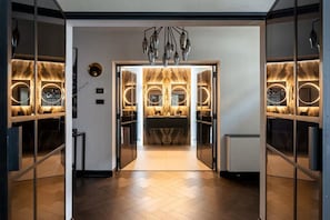 Une salle de bain moderne avec un lavabo central, un meuble-lavabo avec miroir et un luminaire original.