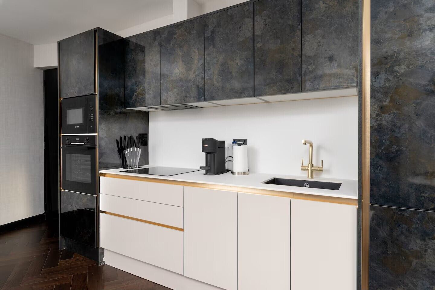 Uma cozinha moderna com forno embutido, máquina de café e pia.