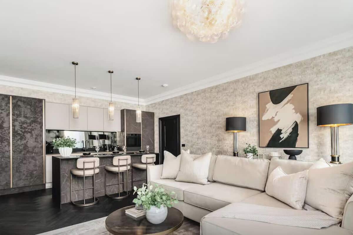 A modern living room with a sofa, coffee table, and a kitchen area in the background.