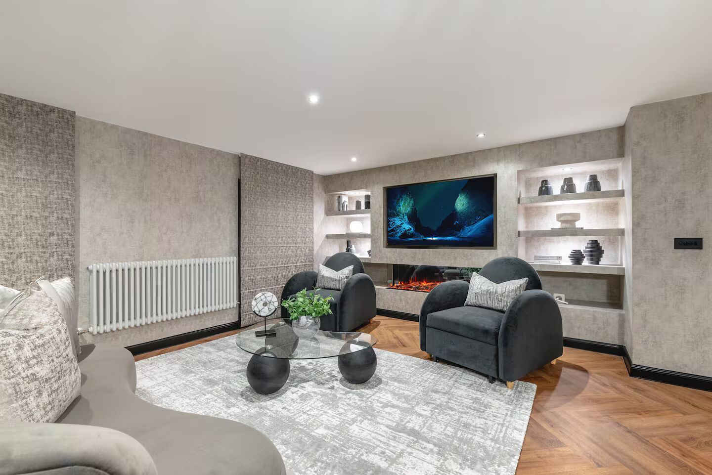 A modern living room with a fireplace, comfortable seating, a flat-screen TV, and a decorative shelf.