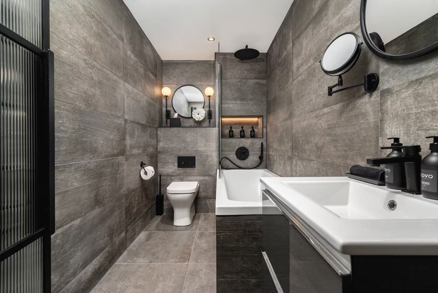 A modern bathroom with a toilet, bathtub, and vanity.