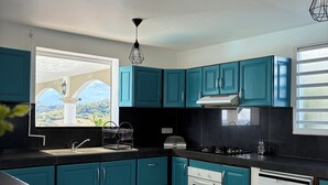 Una cocina moderna con gabinetes color turquesa, encimera negra, estufa, horno y lavavajillas.