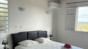Un dormitorio con cama, lámparas de noche, ventana con vistas y ventilador de techo.