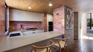 A modern kitchen with a central island, wooden ceiling, and a large window.