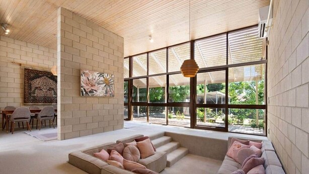A spacious living area with a large window, a sofa, a coffee table, and a dining area with chairs.