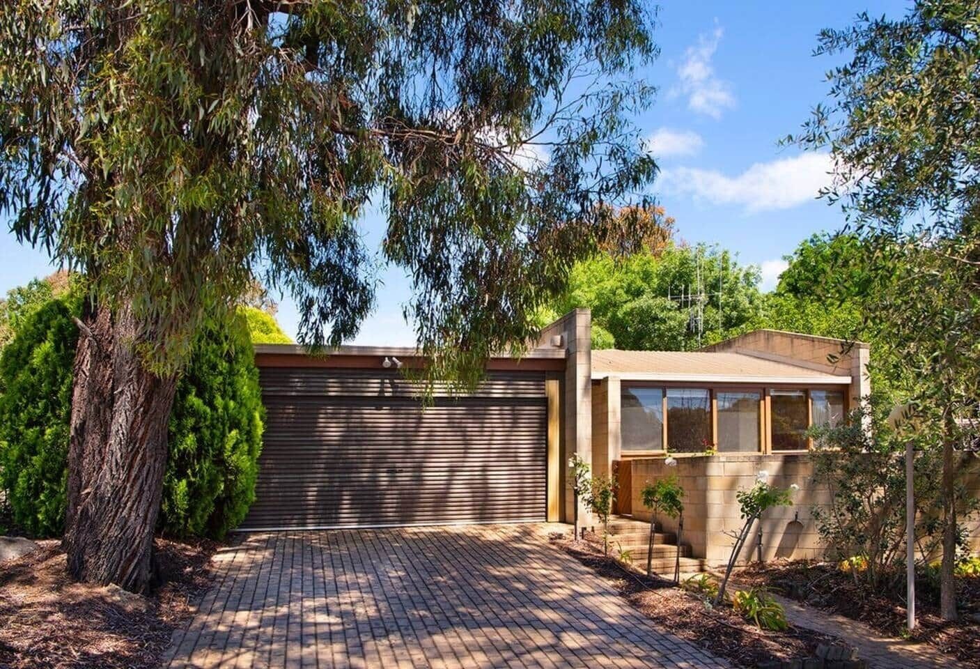 Una casa moderna con entrada de ladrillo, garaje y un pequeño jardín.