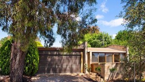 A modern house with a brick driveway, a garage, and a small garden area.