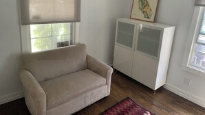 Un soggiorno con un divano beige, un mobile, una finestra con una tenda e una mappa incorniciata al muro.